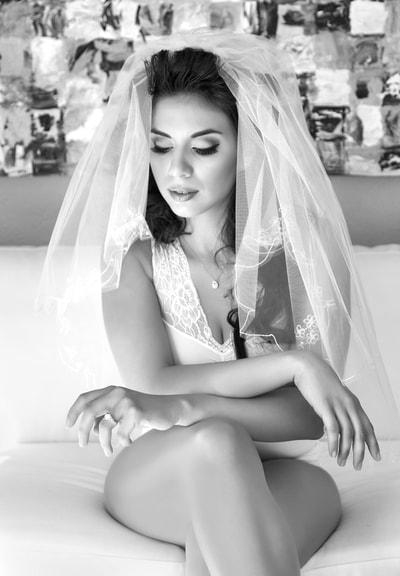 Beautiful young bride wearing lingerie and a veil posing for a bridal boudoir photo shoot