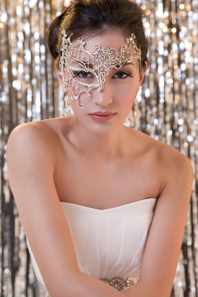 Glamour photo shoot of a young woman wearing a masquerade mask