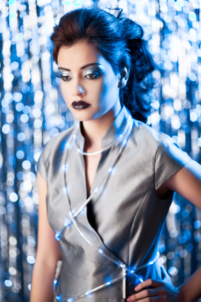 A fashion photo of a young female model posing with LED lights wrapped around her