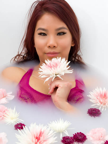 Milk bath photography ideas with a woman holding a flower