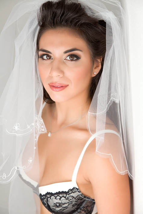 Beautiful young bride wearing a veil in a bridal boudoir photo shoot