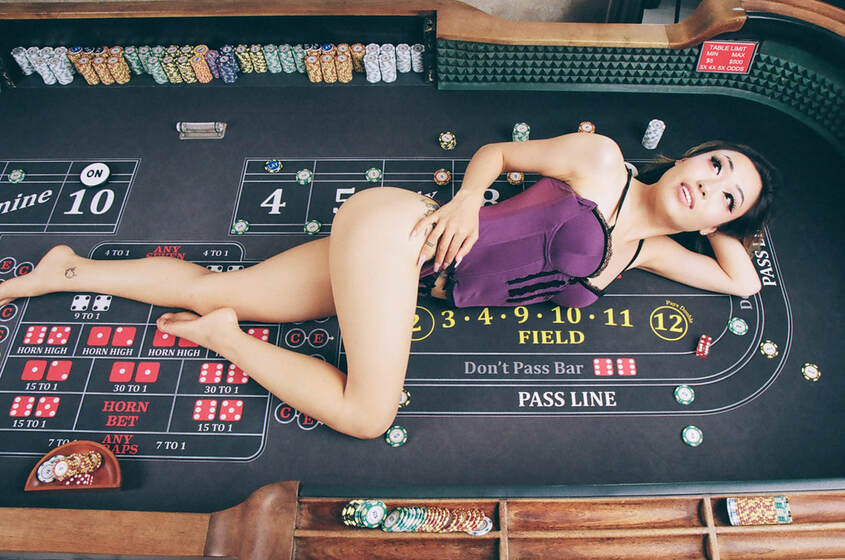 Sexy photo of a young woman wearing a purple lingerie laying on a craps table in Las Vegas during a boudoir photo shoot