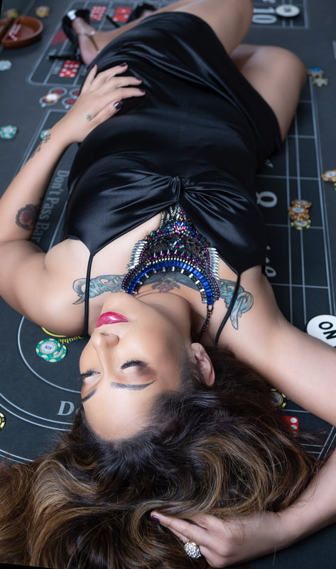 Woman with a chest tattoo wearing a black dress laying on a craps table in Las Vegas 