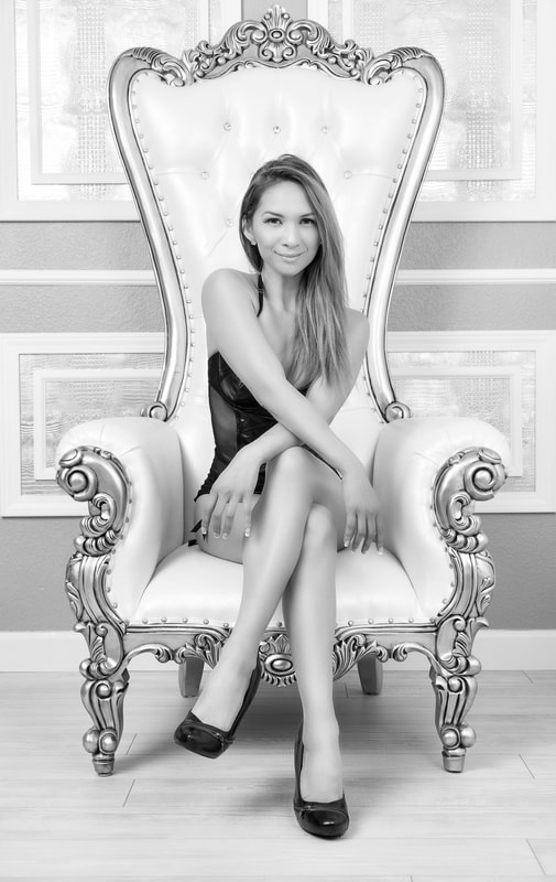Luxury boudoir photo of a young woman wearing black lingerie sitting in a throne chair