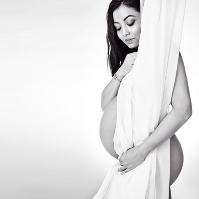 Pregnancy photography Las Vegas of a nude pregnant woman posing behind a sheer white curtain