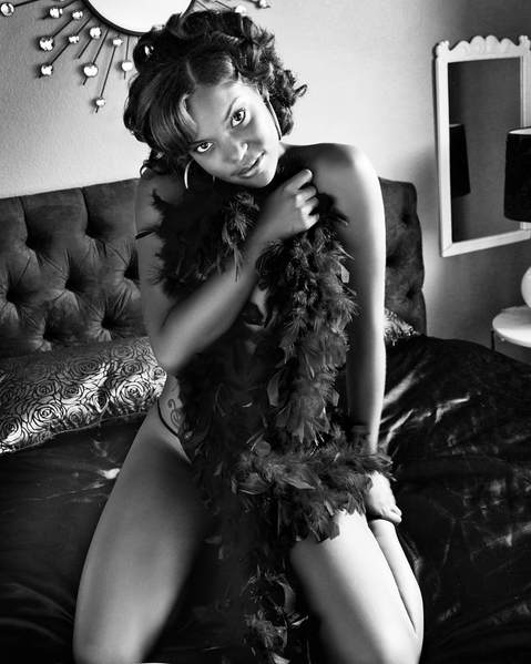 Sexy boudnoir photo of a nude woman covered by a feathered boa