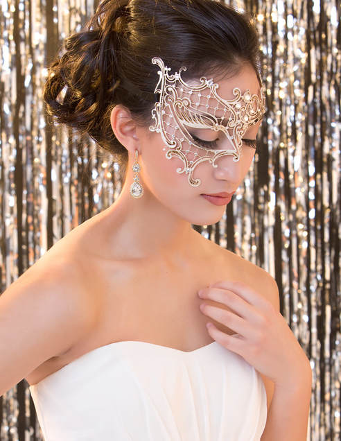 Photo of a beautiful young woman wearing a white dress and a masquerade mask