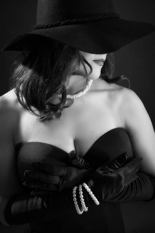 Woman wearing a black hat covering her eyes in a vintage glamour photo