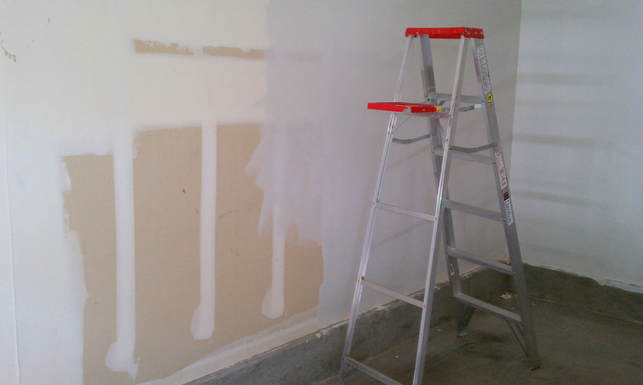 Applying primer to the wall of a DIY boudoir photo studio