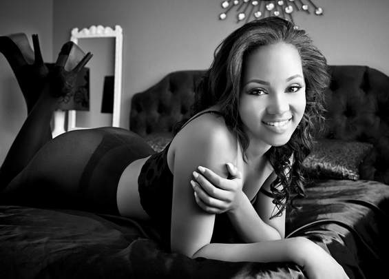 Black and white boudoir photo of a young woman relaxing on a bed